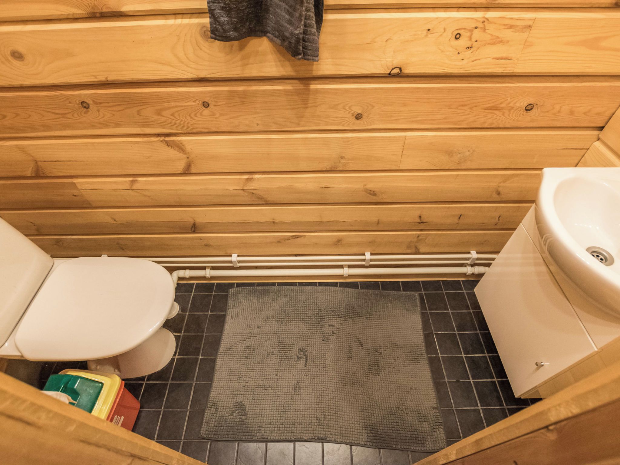 Une salle de bain rustique, aménagée dans une cabane en bois, avec des toilettes, un lavabo et un espace douche.