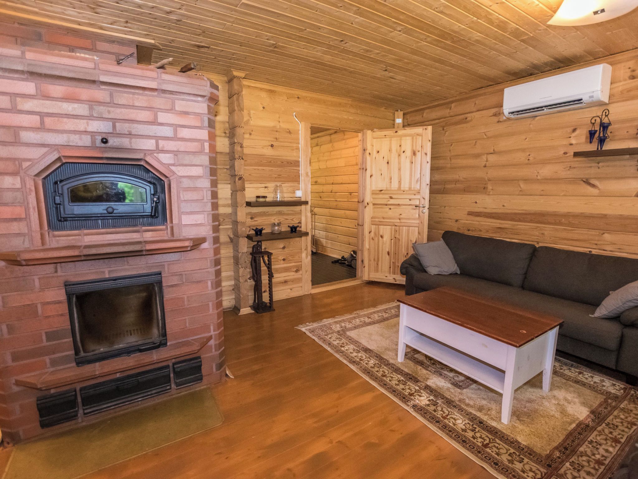 Una sala de estar acogedora con chimenea de ladrillo, paredes de madera, un sofá y una mesa de centro.