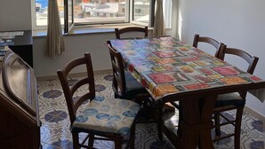 A dining area with a table and chairs, a view of the sea and buildings, and an air conditioning unit on the wall. - Positano Center - Guest 4+2 People in 2 Bedrooms, 2 Bathrooms - AC and WiFi free (Positano)
