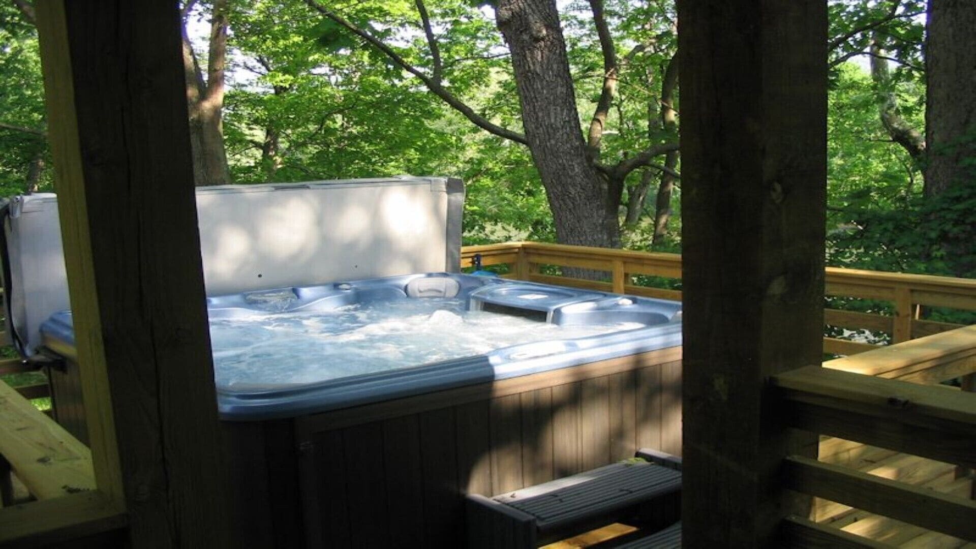 Un bain à remous situé dans un espace boisé, avec une terrasse en bois.