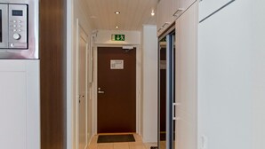 Een gang met een digitale klok, een nooduitgangsbord en een deur met een deurmat.