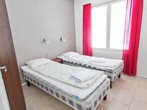 A bedroom with two single beds, a window with red curtains, and a bedside lamp. - Yllästar 3 as 506 by Interhome (Äkäslompolo)