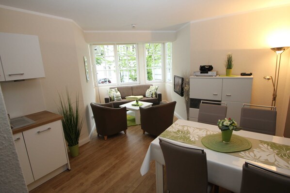 A compact living space with a dining area, kitchenette, and a sofa set.