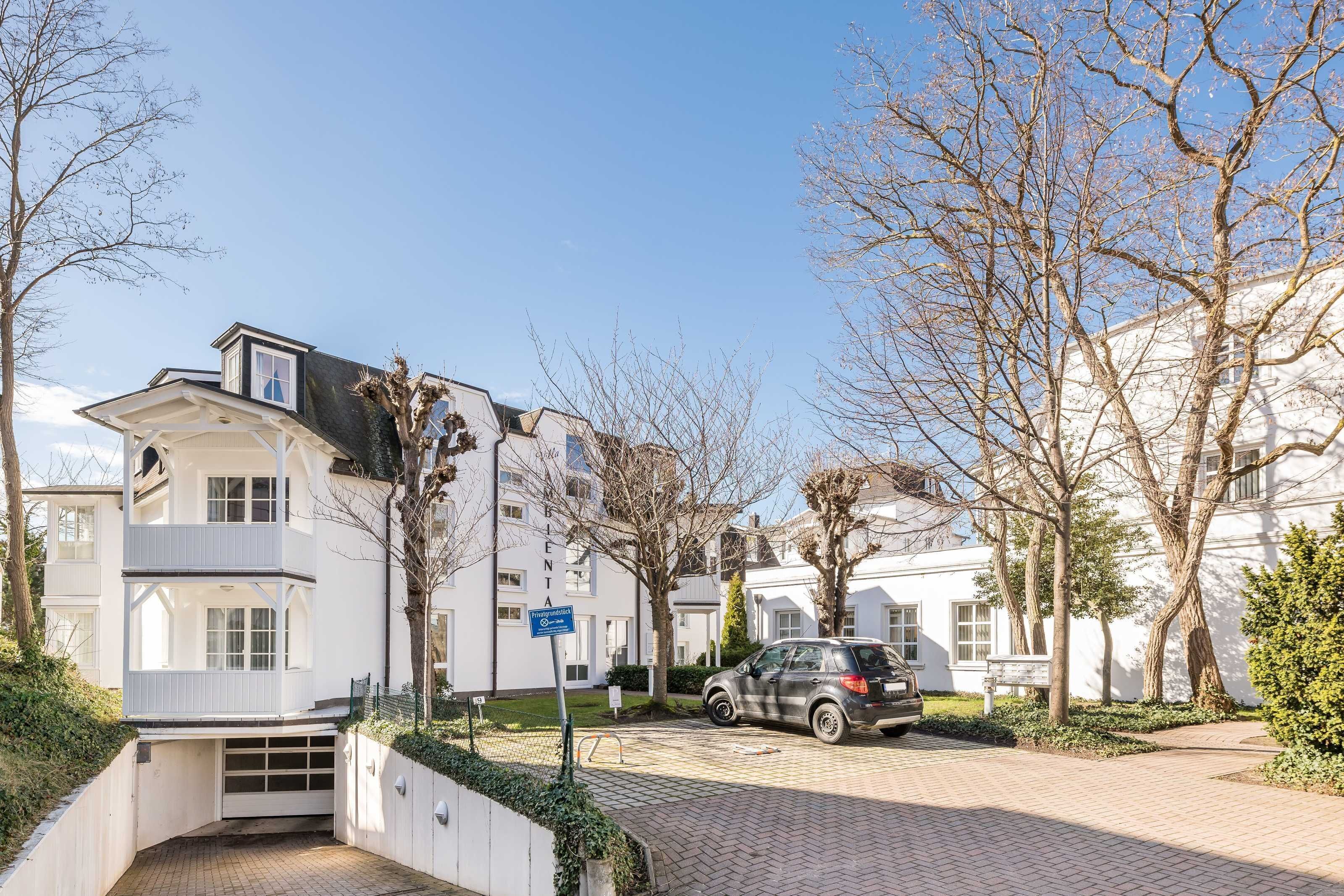 A residential building with a garage, a car parked in front, and a clear sky.