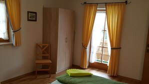 Un dormitorio con una cama, un armario de madera, una silla y cortinas amarillas.