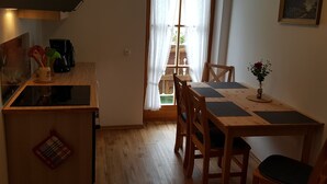 Una cocina compacta con armarios de madera, una cafetera y un comedor con mesa y sillas.