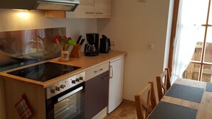 Una cocina compacta con estufa, horno, cafetera y un mueble pequeño.