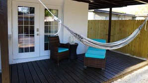 A covered patio with a hammock, wicker furniture, and a door. - Experience the passion of hospitality, cleaning, and good location! (Tampa)