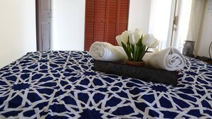 A bed with a patterned blue and white bedspread, a rolled white towel, and a small plant with white flowers. - Experience the passion of hospitality, cleaning, and good location! (Tampa)