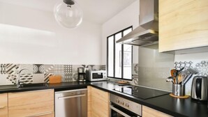 A modern kitchen with wooden cabinets, a stainless steel dishwasher, a microwave, and an oven. - Le Clos Marin by Interhome (Saint Cyr sur mer Les Lecques)