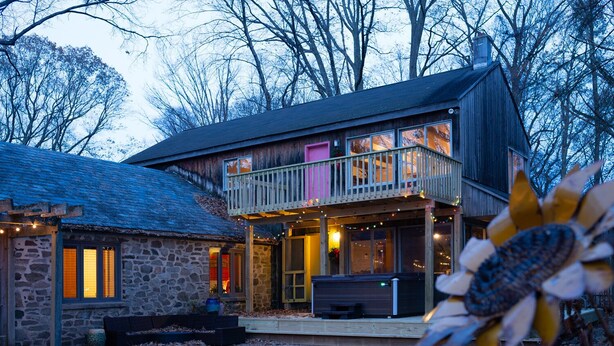 A two-story wooden house with a balcony, stone exterior, and a covered patio area. - Mountain House -  A private rustic oasis with goats!  (New Hope)