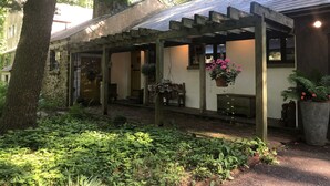 A rustic stone building with a covered porch, hanging flower baskets, and a brick pathway. - Mountain House -  A private rustic oasis with goats!  (New Hope)