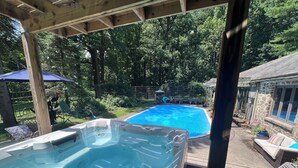A hot tub and a swimming pool in a backyard with a wooden deck, surrounded by greenery and a stone building. - Mountain House -  A private rustic oasis with goats!  (New Hope)