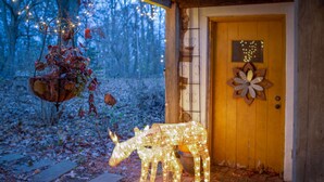 A wooden door with a decorative metal sign, a lighted horse sculpture, and a hanging light fixture with dried leaves. - Mountain House -  A private rustic oasis with goats!  (New Hope)
