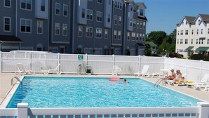 Una piscina rettangolare con recinzione bianca, sdraio e una persona che nuota.