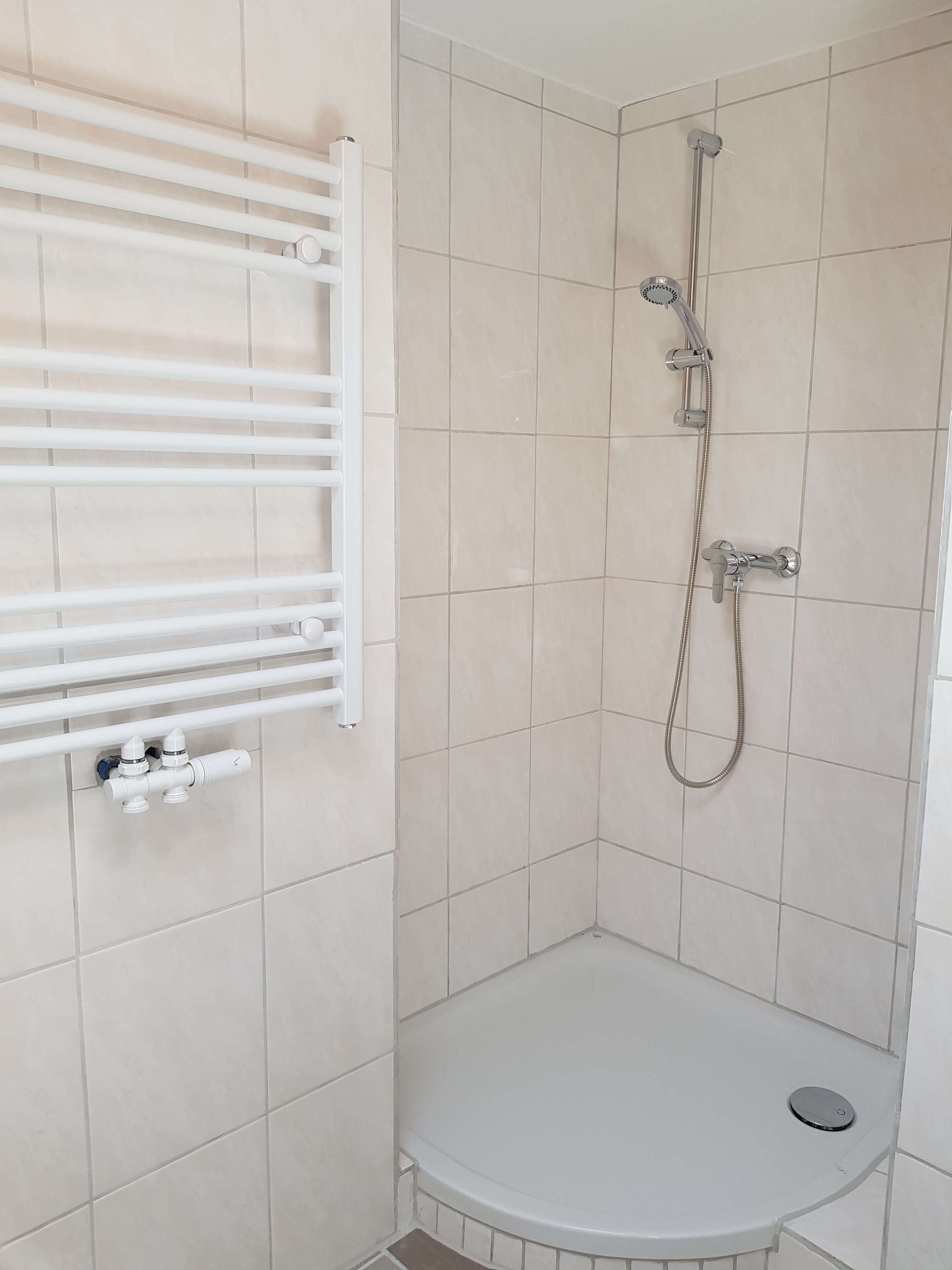 A bathroom with a shower, a toilet, and a towel rack.