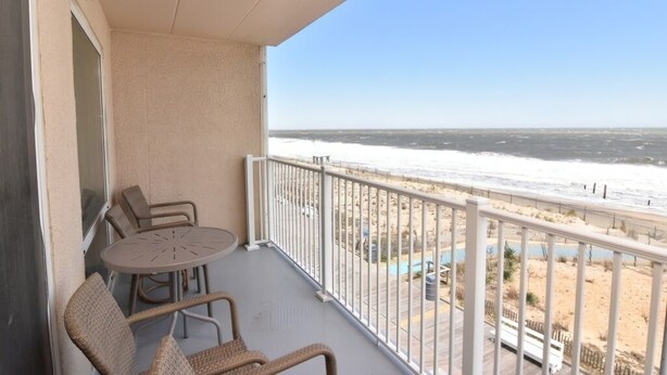 A balcony with a view of the beach and ocean.