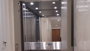 A modern elevator with metallic finish and glass doors, leading to a well-lit interior. - Tourist apartments (Mota del Cuervo)