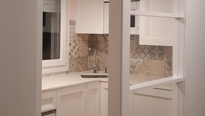 A modern kitchen with white cabinetry, a hanging pendant light, and a patterned backsplash. - Tourist apartments (Mota del Cuervo)