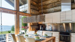 A modern kitchen with wooden cabinets, a stainless steel stove, and a dining area with a wooden table and chairs. - Villa pärla by Interhome (Olhava)