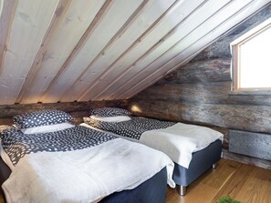 A room with two beds, wooden beams on the ceiling, a window, and a stone wall. - Villa pärla by Interhome (Olhava)