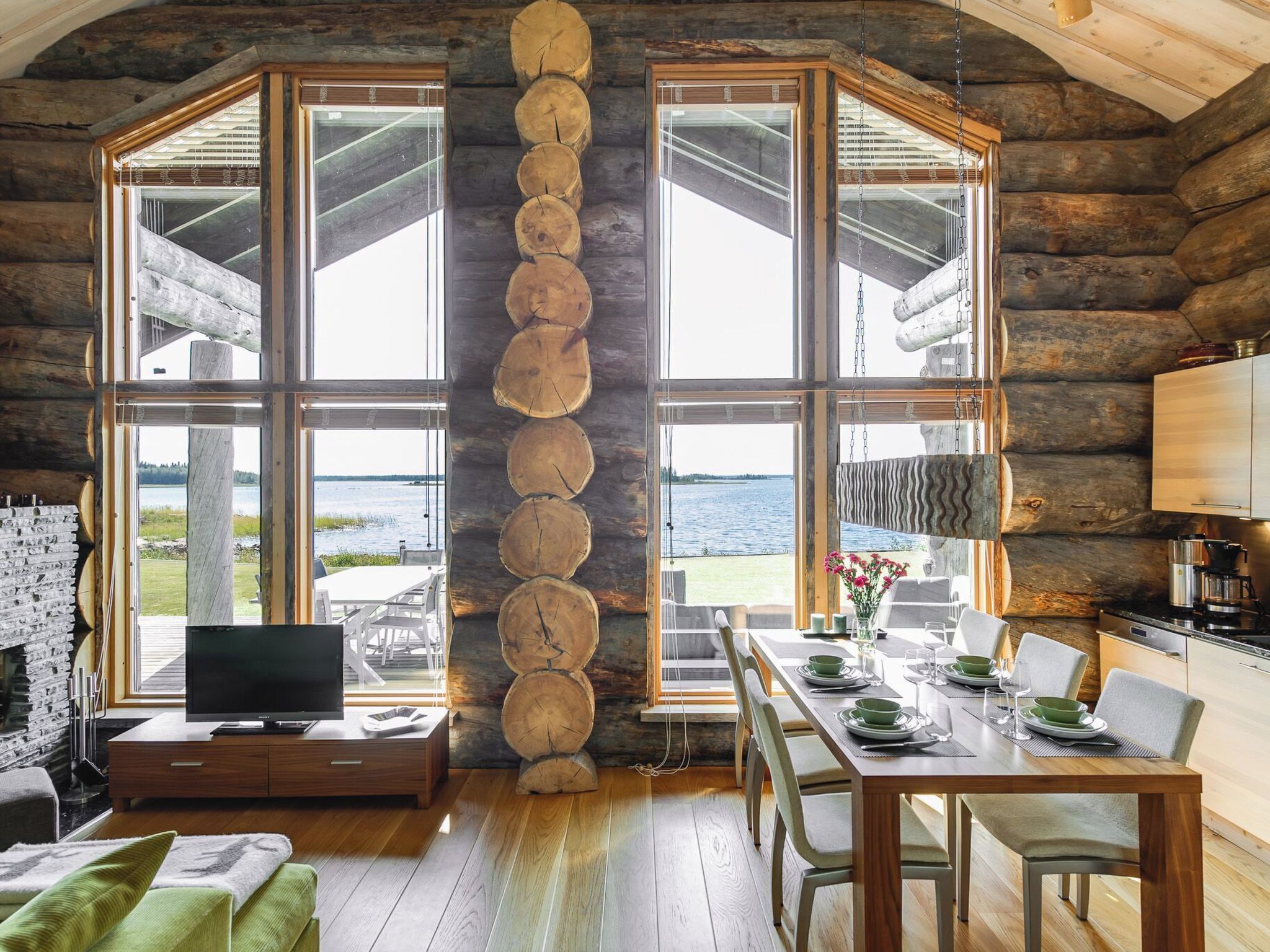 L’intérieur d’une cabane en rondins comprend un coin repas, une cuisine et une grande fenêtre donnant sur un plan d’eau.