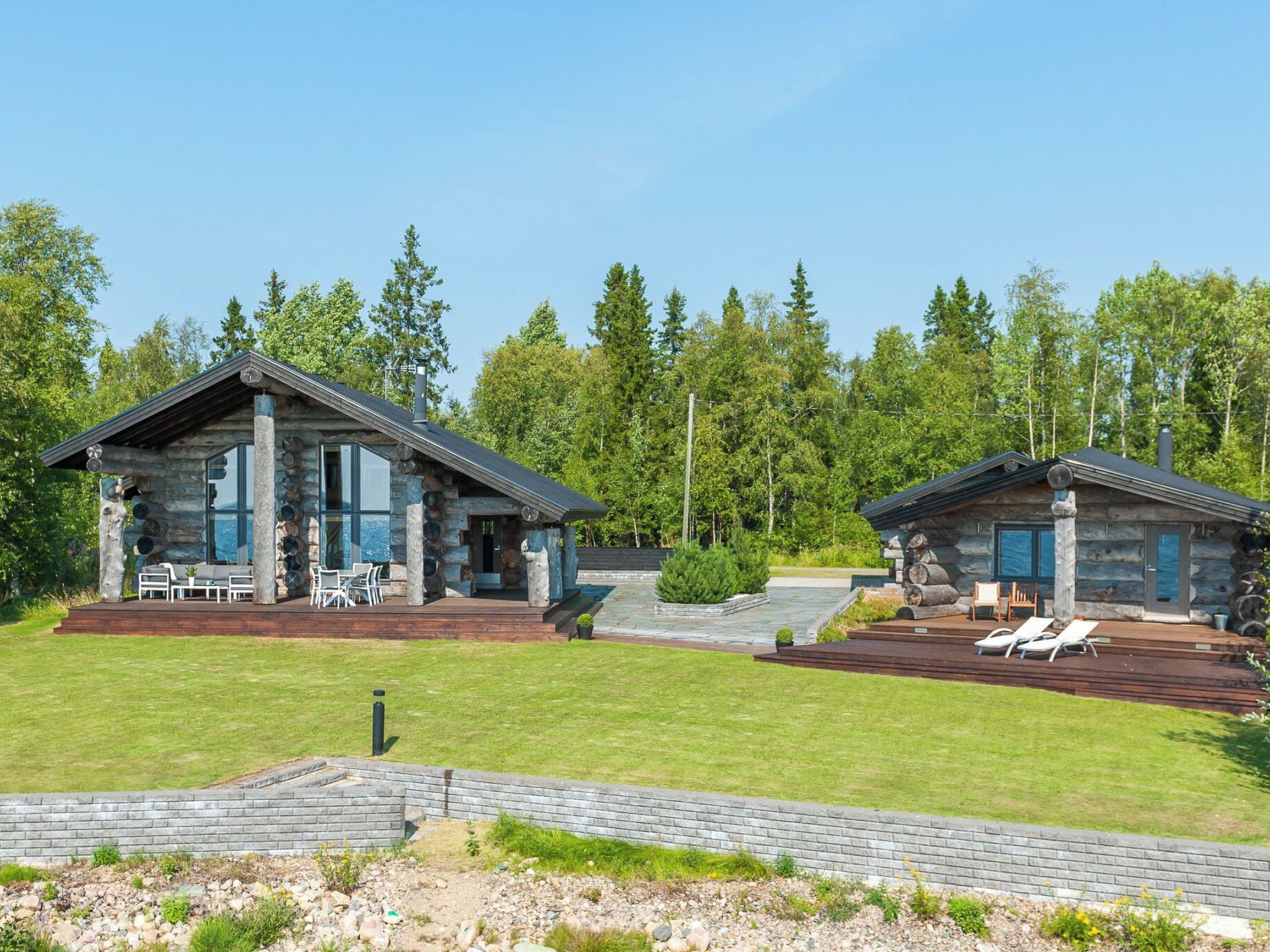 A modern log cabin with a deck and outdoor seating area.