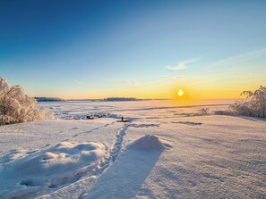 Schneebedeckte Landschaft mit klarem Himmel und untergehender oder aufgehender Sonne.