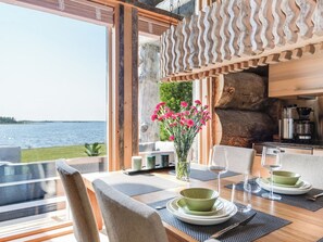 A dining area with a view of the water, a table set with plates, glasses, and a vase with flowers. - Villa pärla by Interhome (Olhava)