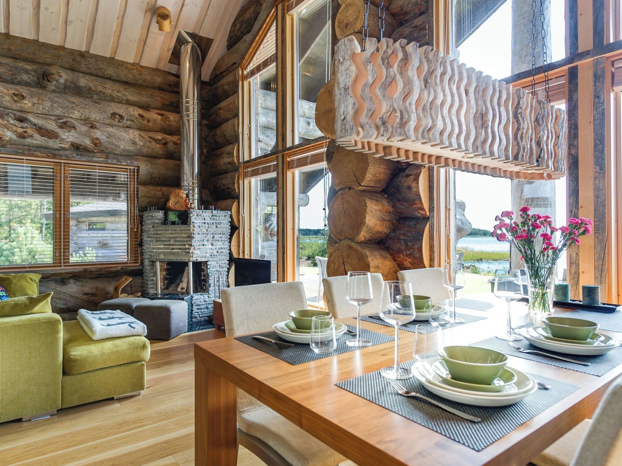Ein gemütliches Blockhaus-Interieur mit Essbereich, Holzmöbeln und einem Kamin aus Stein.