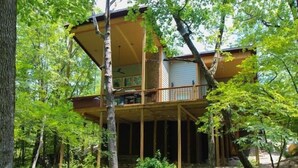 A two-story wooden cabin surrounded by trees.