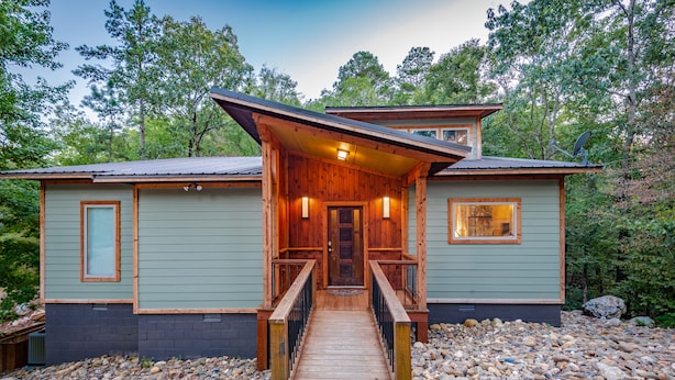 A cabin with a wooden deck, a front door, and a satellite dish.