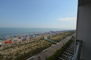 A beach with numerous umbrellas and people, a wooden boardwalk, and a view of the ocean. - Edgewater House - Ocean Front Units With Spectacular Views! (Rehoboth Beach)