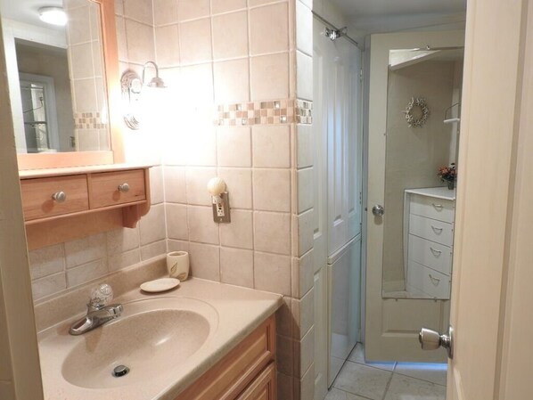 A bathroom with a sink, mirror, and a shower area.