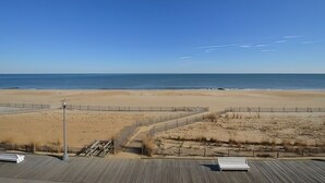 Vista a la playa con un paseo de madera y una valla.
