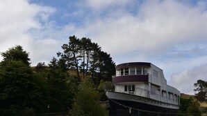 A stationary boat with a cabin structure, surrounded by trees and a clear sky.