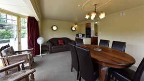 A dining area with a wooden table and chairs, a sofa, and a fan.