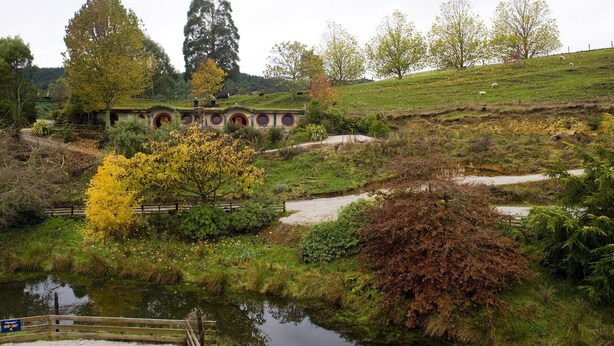 Un parc sur le thème de la Comté, avec une maison à l’image de celles de la Comté, un étang et une colline verdoyante parsemée d’arbres.