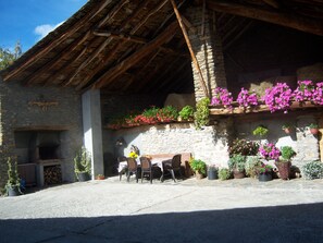 A rustic stone building with a wooden roof, outdoor seating area, and potted plants. - Casa Rural Rogel (full rental) for 7 people in Llessui-Sort- Pirineos (Llessui)