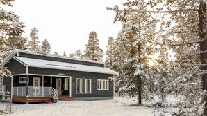 Une cabane à deux étages avec un porche et une all ée enneigée.