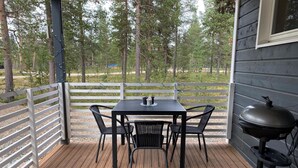 Une terrasse en bois avec une table et des chaises, un barbecue et une clôture blanche.