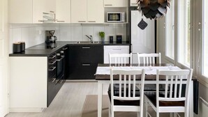 Une cuisine moderne avec des meubles blancs, un plan de travail noir et un coin repas comprenant des chaises et une table blanches.