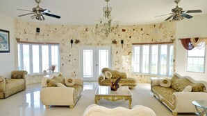 Een ruime woonkamer met een stenen muur, twee banken, een salontafel en plafondventilatoren.