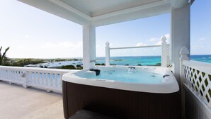 Een bubbelbad op een balkon met uitzicht op de oceaan en boten.