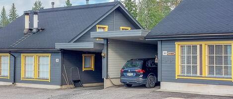 A two-story building with a garage, a ladder, and a parked SUV.