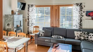 Ein Wohnzimmer mit grauem Sofa, Holzstühlen, einem Esstisch und einem Kamin.