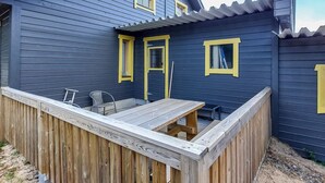 Ein zweistöckiges Haus mit einer Holzterrasse und einer kleinen Terrasse.