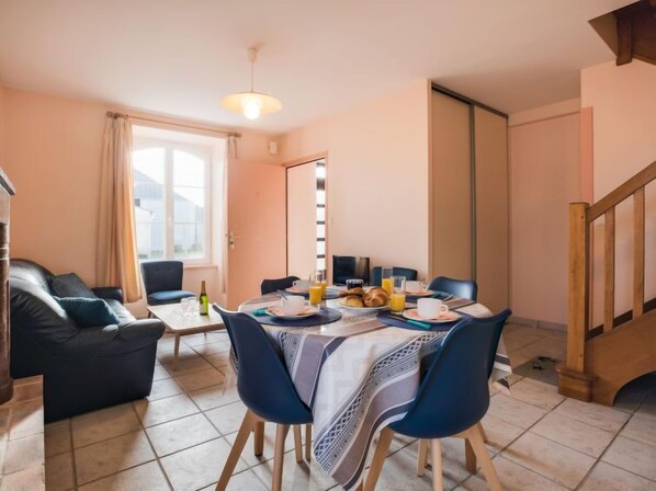 A dining area with a table set for breakfast, including croissants and orange juice. There is a sofa and a window with curtains in the background. - Beaumer by Interhome (Carnac)