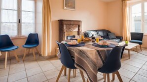 Un comedor con una mesa dispuesta para cuatro, chimenea y vistas al exterior a través de amplios ventanales.