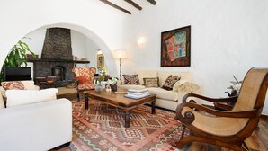 A living room with a fireplace, a sofa, a coffee table, and a patterned rug. - Rustic Home Short Drive from Beach with Pool, Terraces & Garden (Güime)